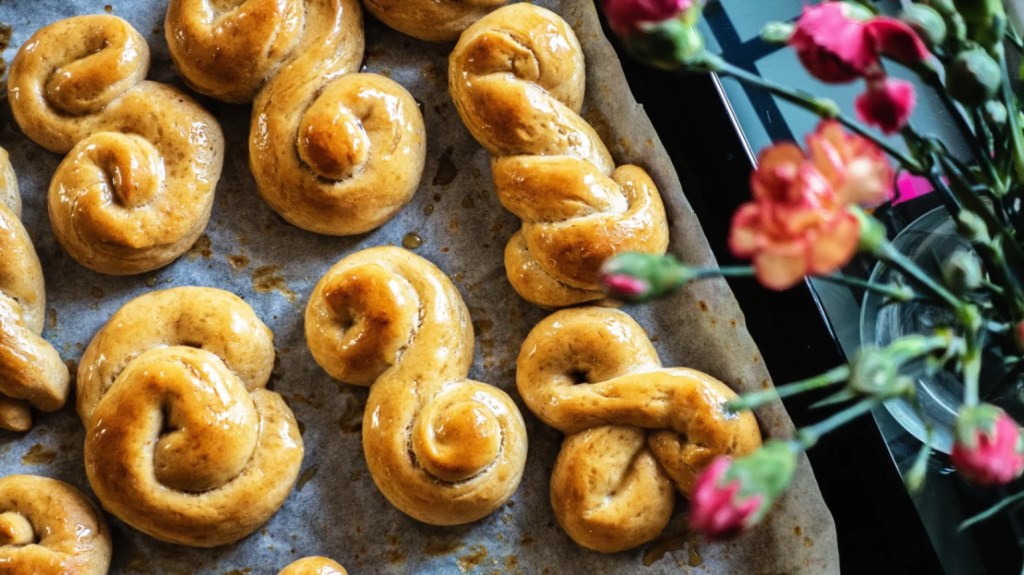 Złociste, zawijane drożdżówki na papierze do pieczenia, lśniące od syropu lub glazury, świeżo upieczone.