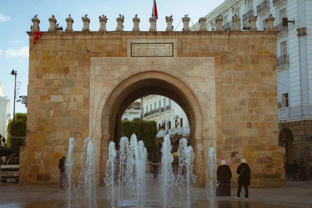 Brama morska Bab El Bhar w Tunisie z wystrzeliwującymi małymi fontannami na pierwszym planie.
