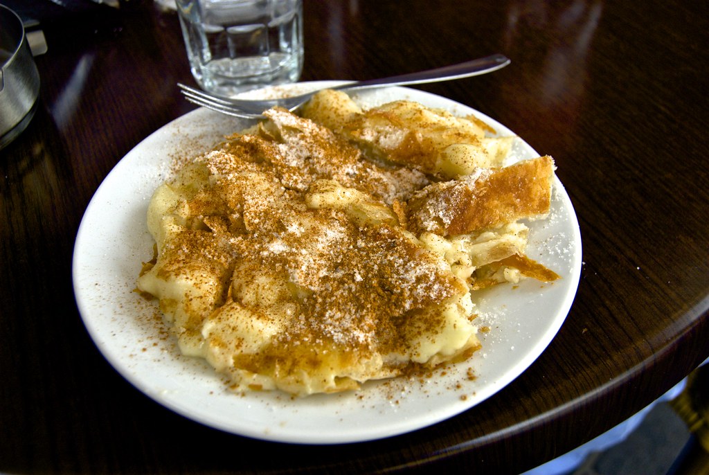 Bougatsa podana na talerzu, posypana cukrem pudrem i cynamonem – tradycyjne greckie ciasto z nadzieniem.