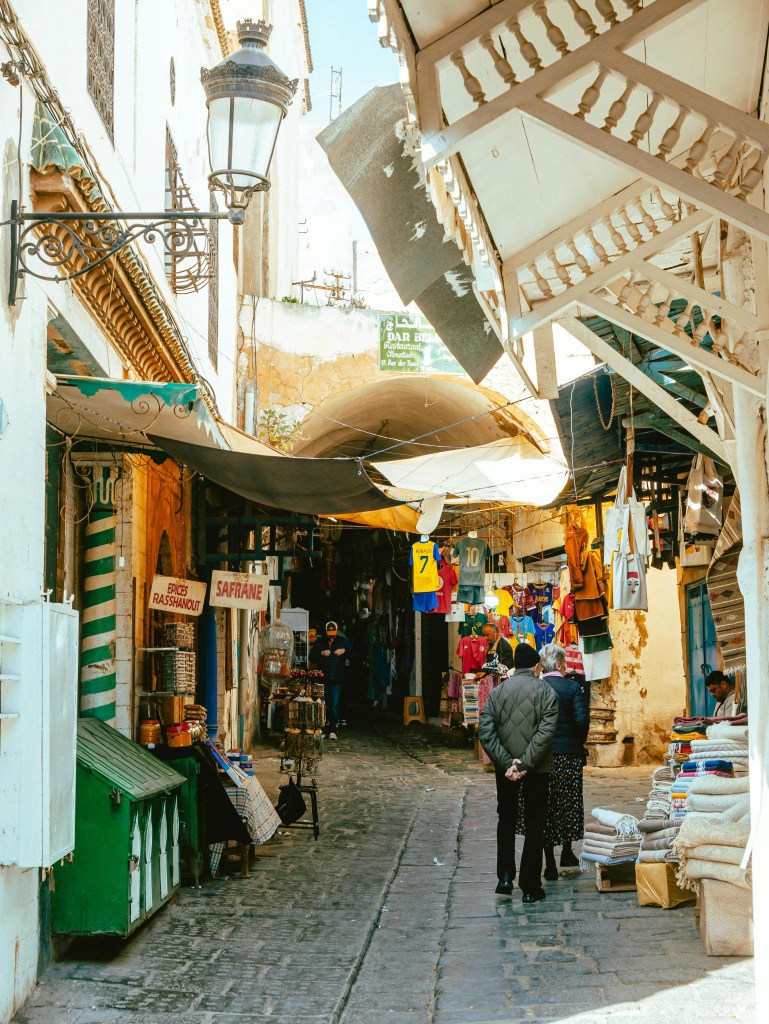 Ulica w medynie Tunisu z licznymi sklepami i wiszącymi produktami.