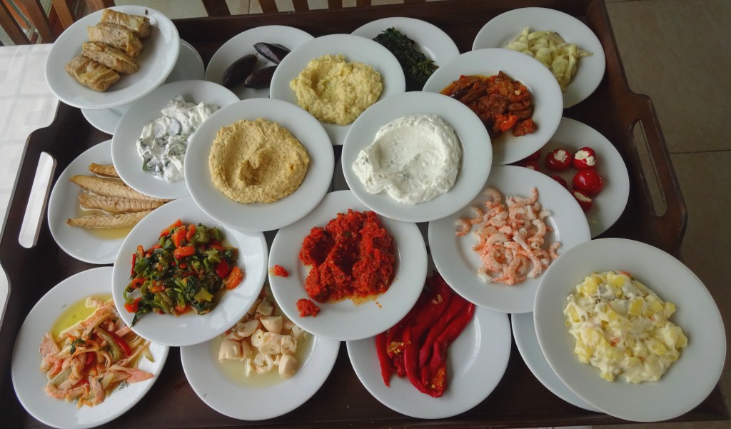 Zestaw meze z Krety – różnorodne klasyki kuchni regionalnej podane na małych talerzykach, w tym sery, oliwki, pasty i warzywa.