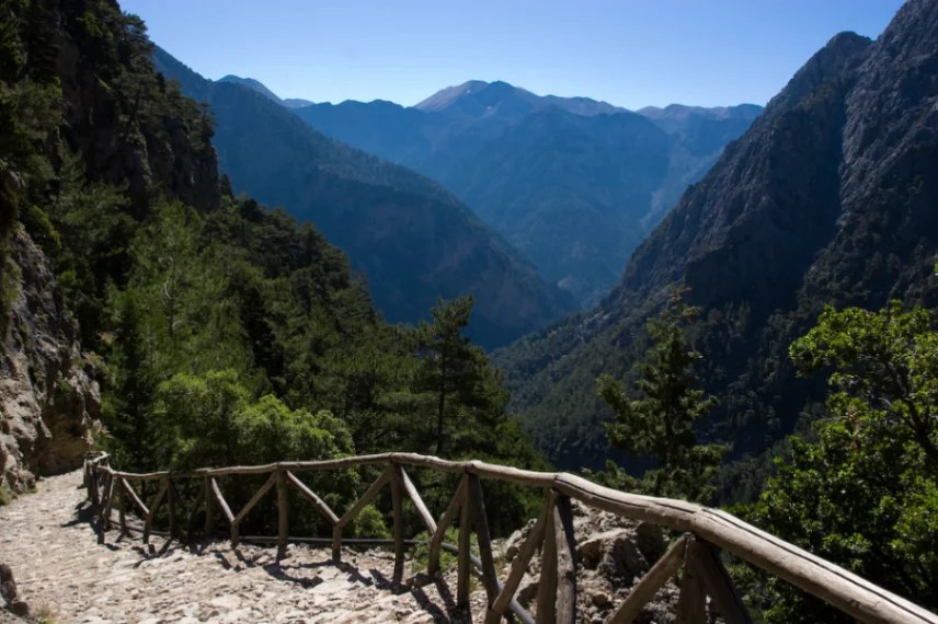 Zejście do wąwozu Samaria z kamienną ścieżką prowadzącą w dół, otoczone zielonymi górami Krety.